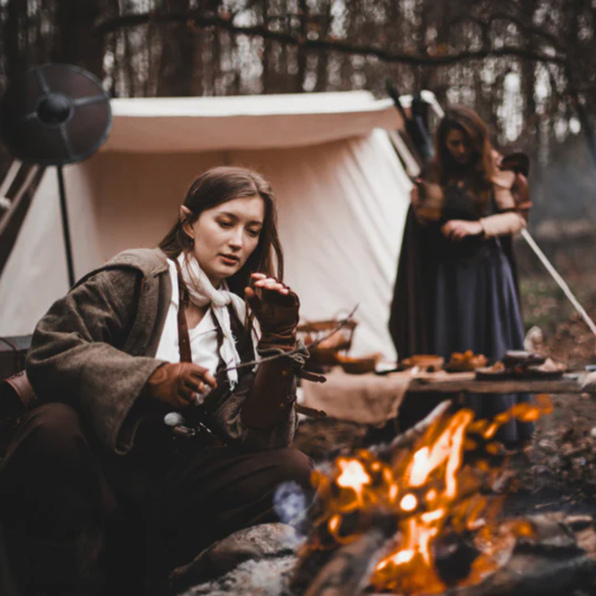 What is LARP? Scene of participants enjoying a fire while dressed in fantasy costumes in a wooded setting.