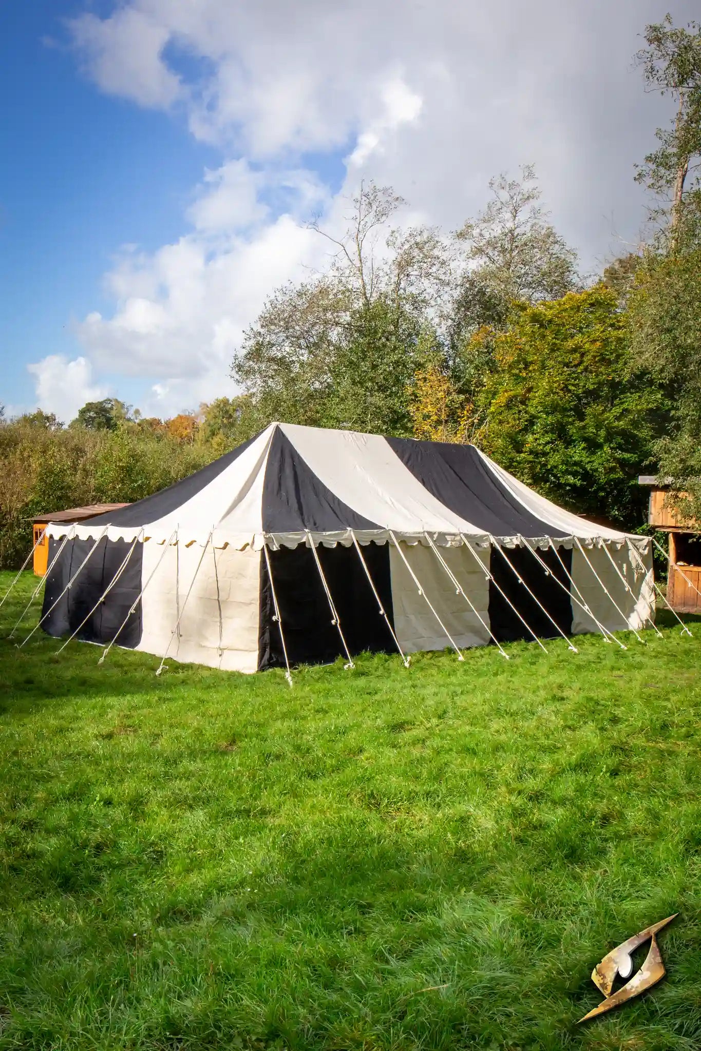 Medieval Tents set up in a grassy area, featuring a black and white canvas design against a blue sky.