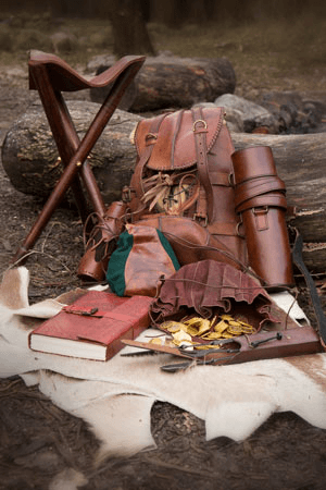 Character Accessories including leather backpack, pouch, book, and various gear on a rustic setting.