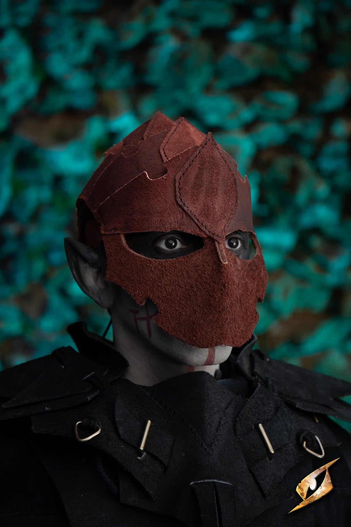 Assassin helmet - Suede worn by a character with a dark outfit and unique design, set against a green backdrop.