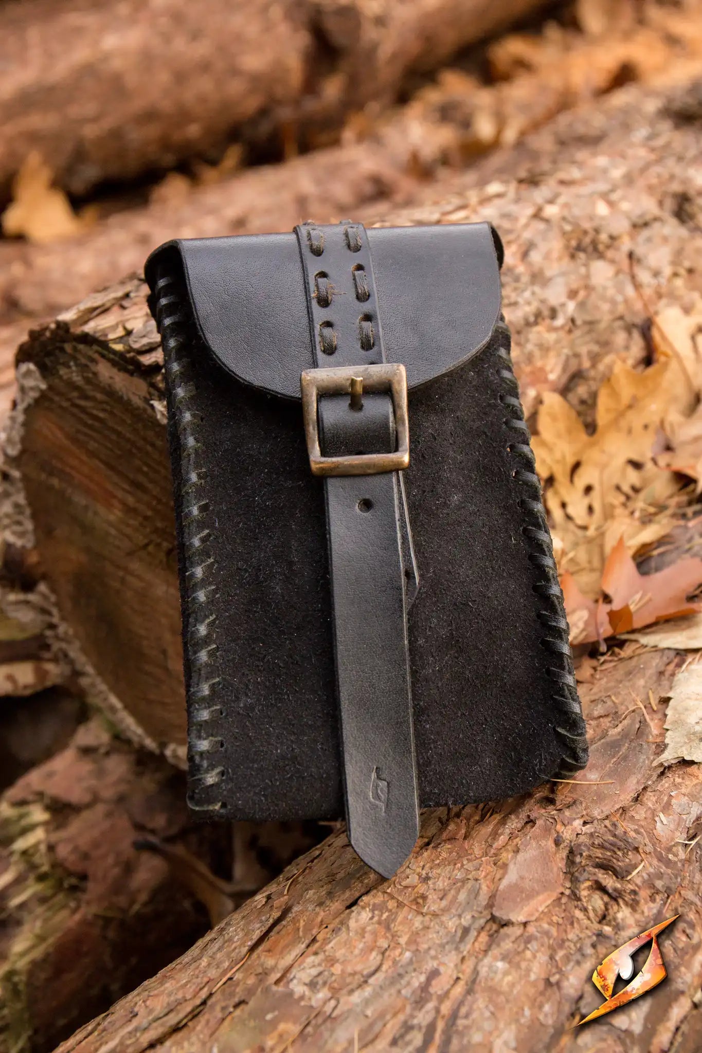 Merchant Suede Bag displayed on wooden logs, featuring a unique buckle closure and intricate stitching details.