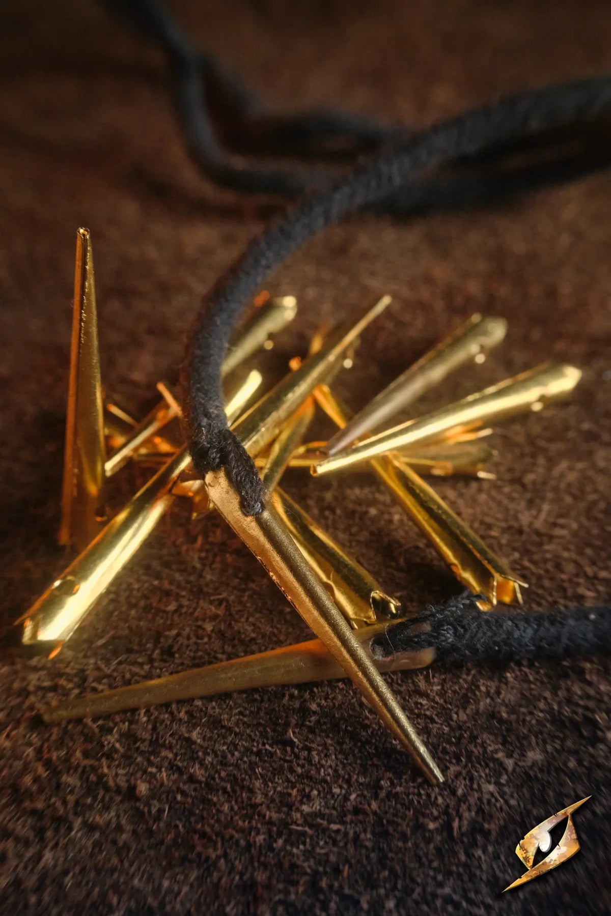 Tie String Points - Bag of 10 with gold-colored points and a black string on a textured background.