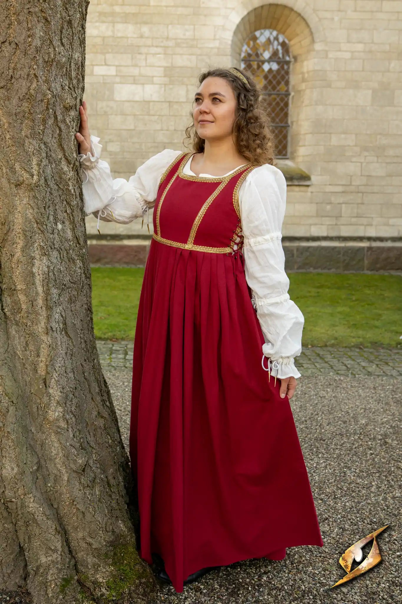 Woman wearing Dress Lucrezia standing by a tree in a picturesque outdoor setting.