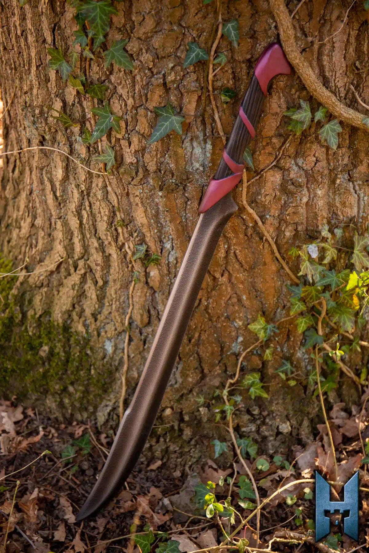 Elven Hunter Blade resting against a tree, showcasing its sleek design and craftsmanship in a forest setting.