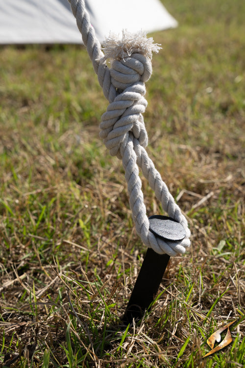 V-Shape Iron Peg B securing a tent guy line in grass for stability during harsh conditions.