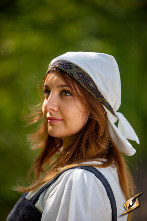 Young woman wearing an Estrid Scarf, showcasing its intricate design and historical significance in a natural setting.