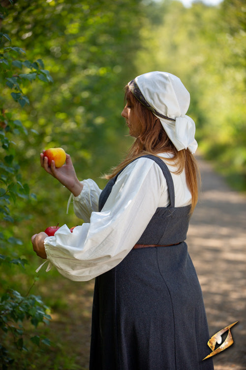 Estrid Scarf worn by a villager holding apples in a lush countryside.