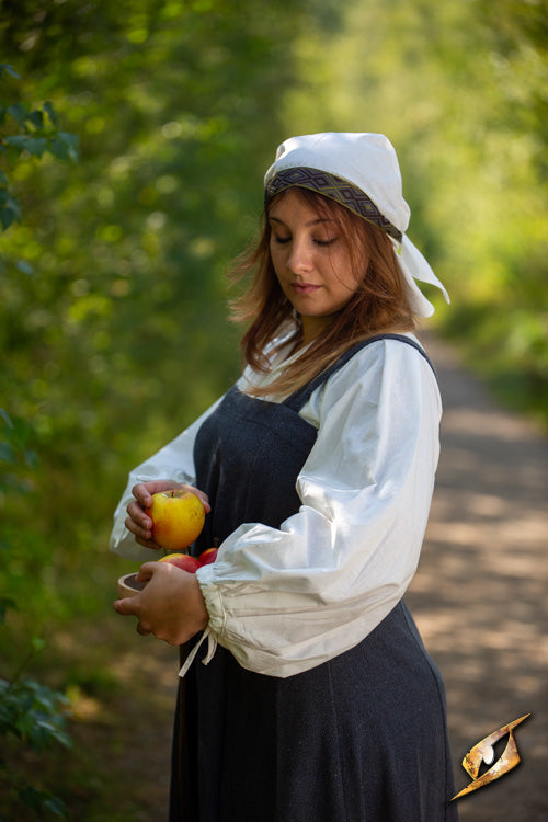 Woman in period clothing holding apples in a forest, symbolizing the historical vibe of the Estrid Scarf.