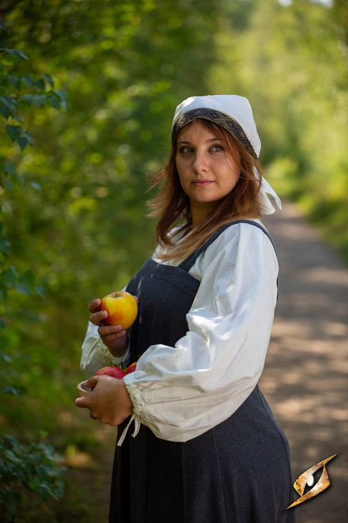 Woman holding apples on a path, wearing the Estrid Scarf while embodying strength and resolve.