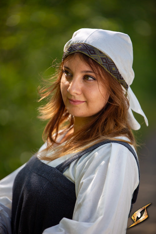 Person wearing a traditional cap and clothing reminiscent of the Estrid Scarf style, reflecting historical themes.