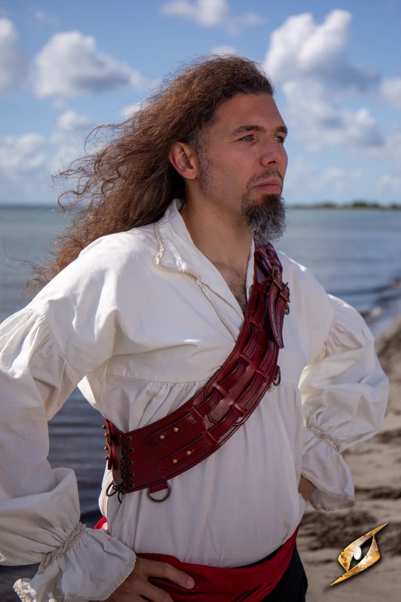 Man wearing a Bandolier of Many Adventures against a coastal backdrop, embodying rugged adventure and readiness.