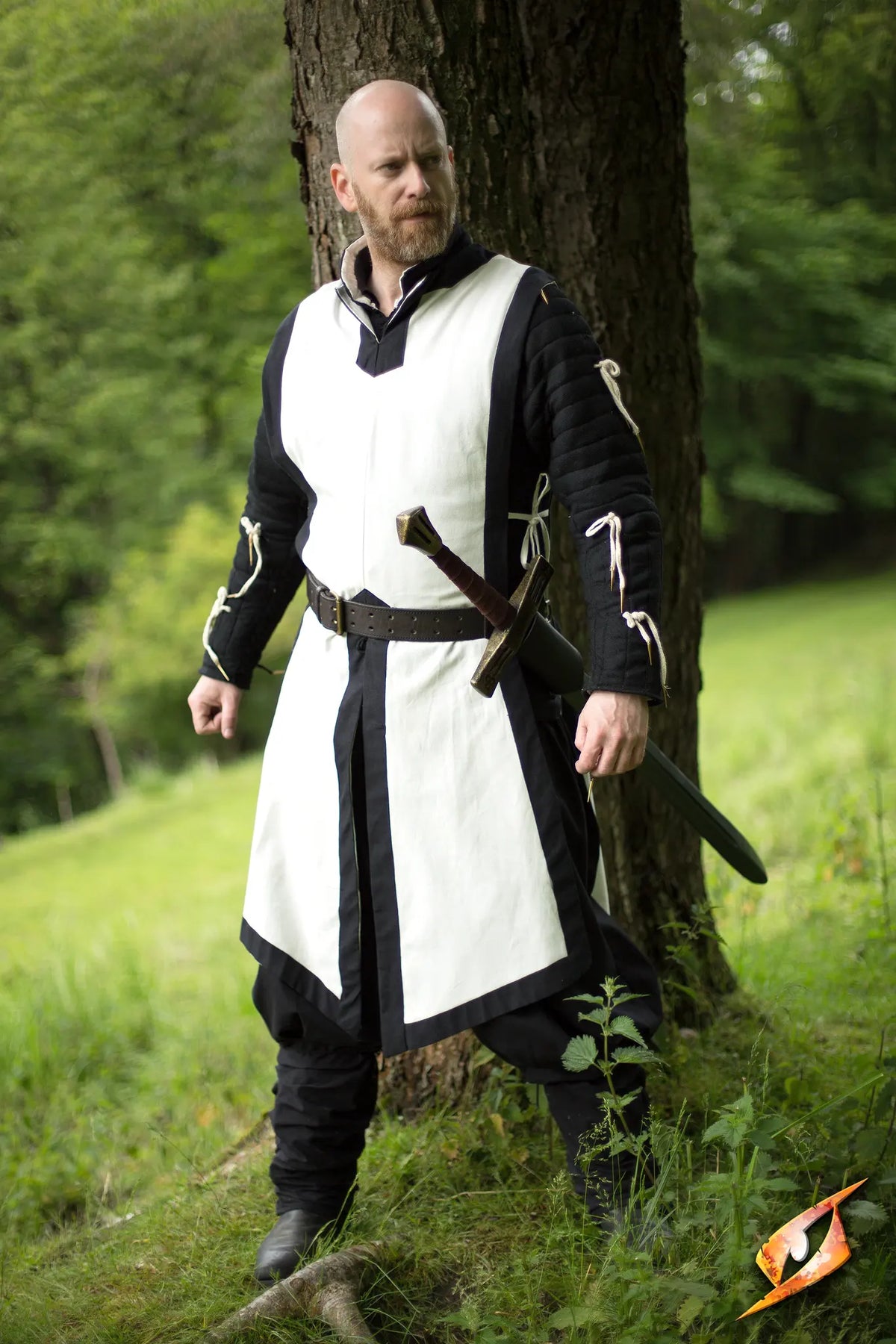 A knight wearing a Basic Tabard over armor, poised with a sword in a forest setting, ready for battle.