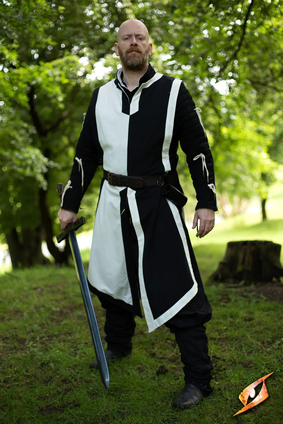 A brave knight in a Basic Tabard stands confidently with a sword, ready for battle in an outdoor setting.