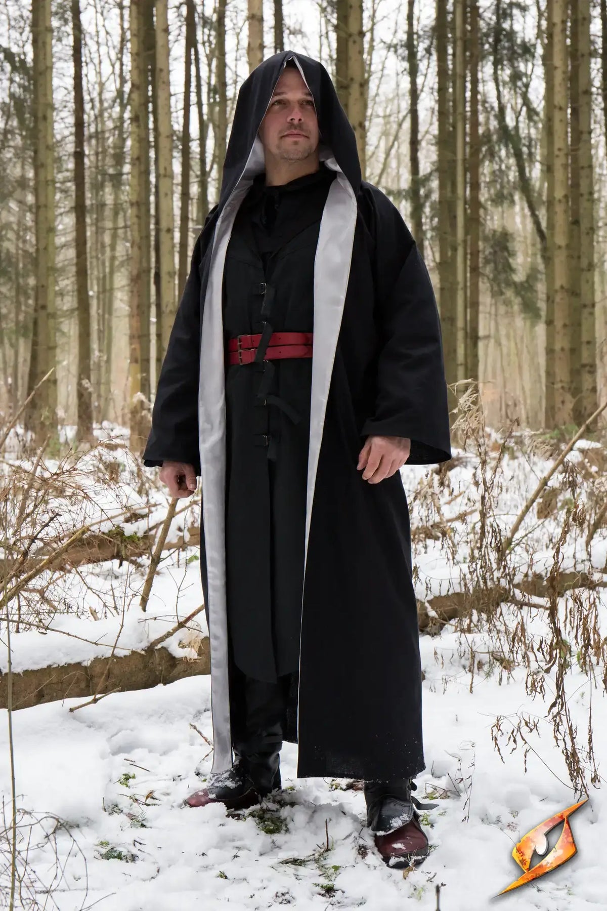 A person wearing a black Magician Robe with a hood, standing in a snowy forest, exuding a magical aura.