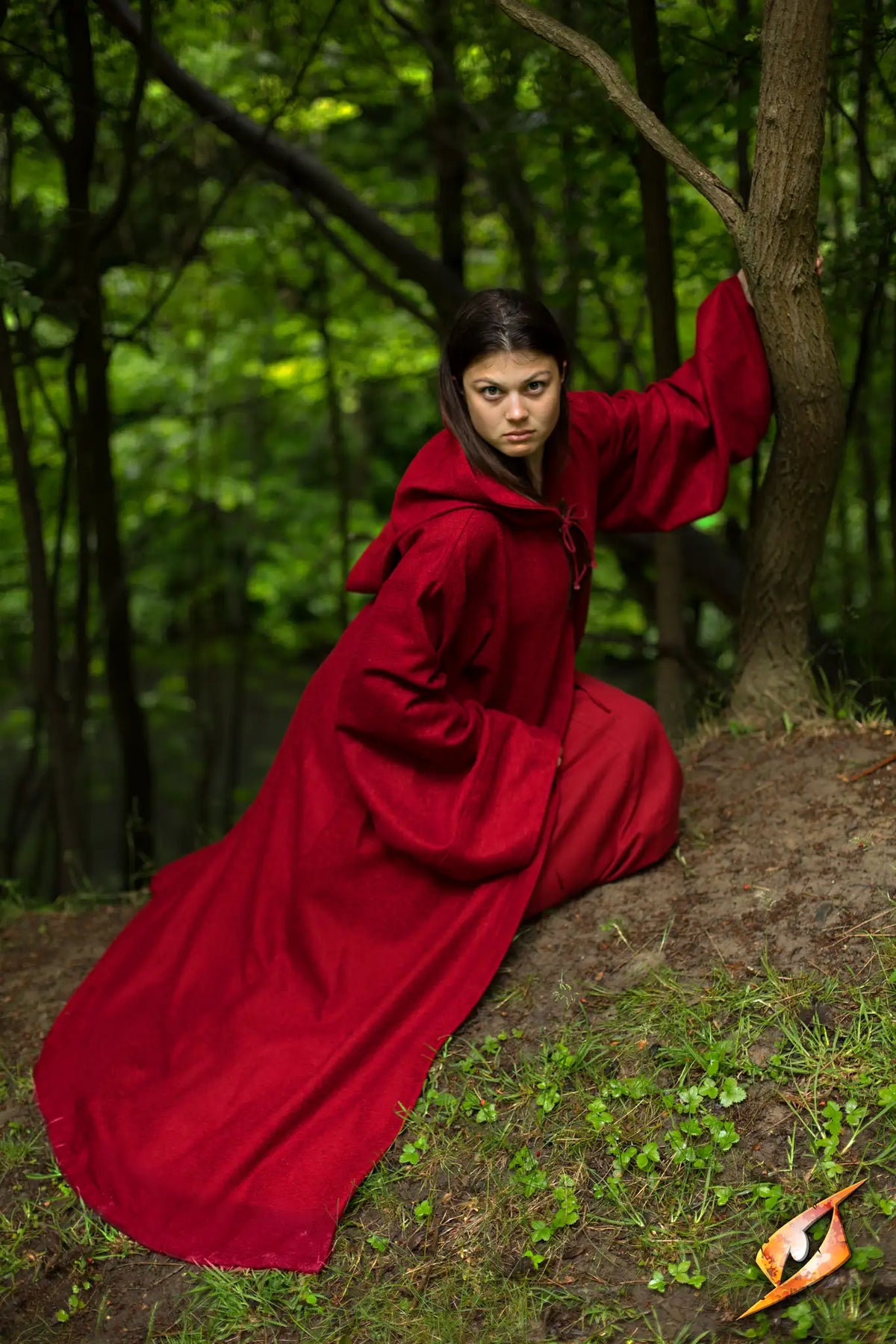 Robe Benedict worn by a woman in a forest, showcasing its striking red color and hooded design.