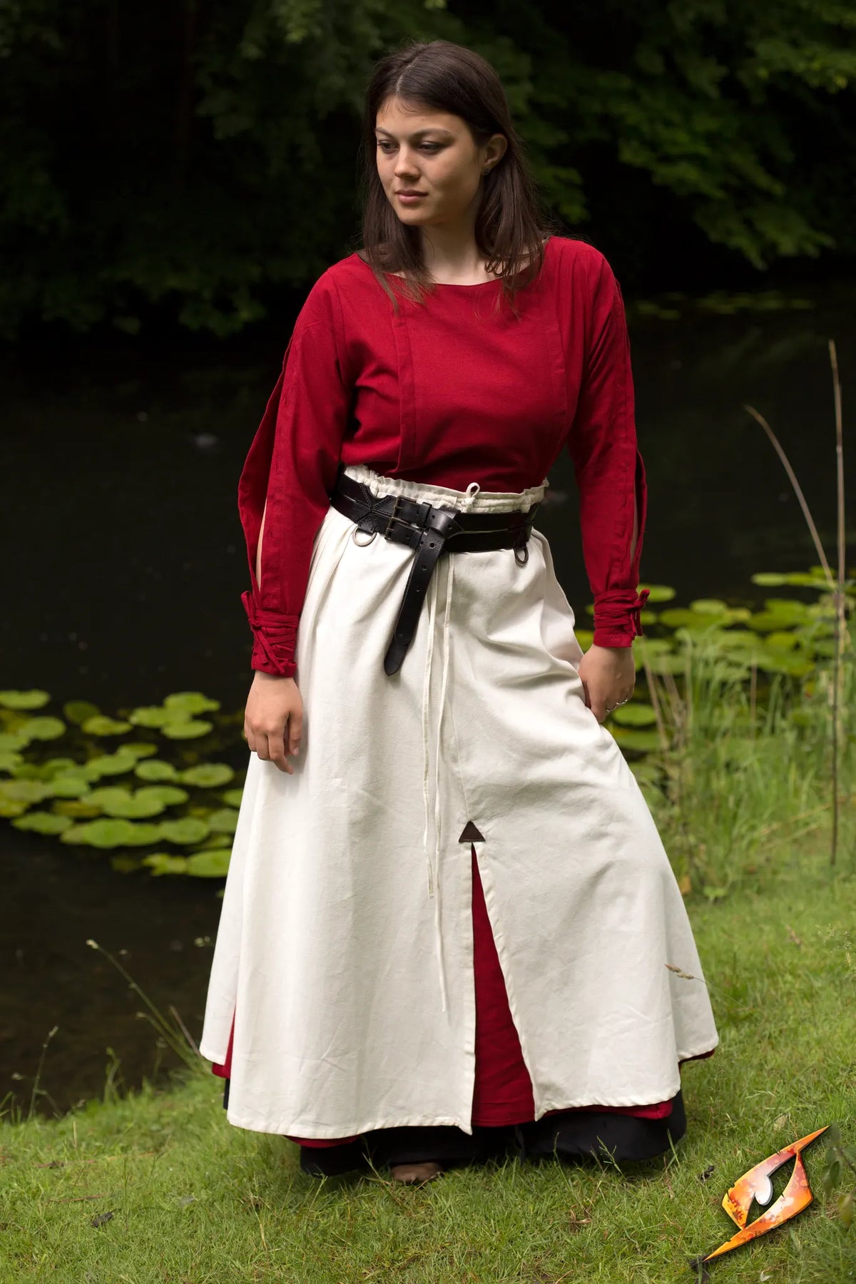 Model wearing a red top and an Epic Armoury Battle Skirt by a pond, showcasing the skirt's design and movement.