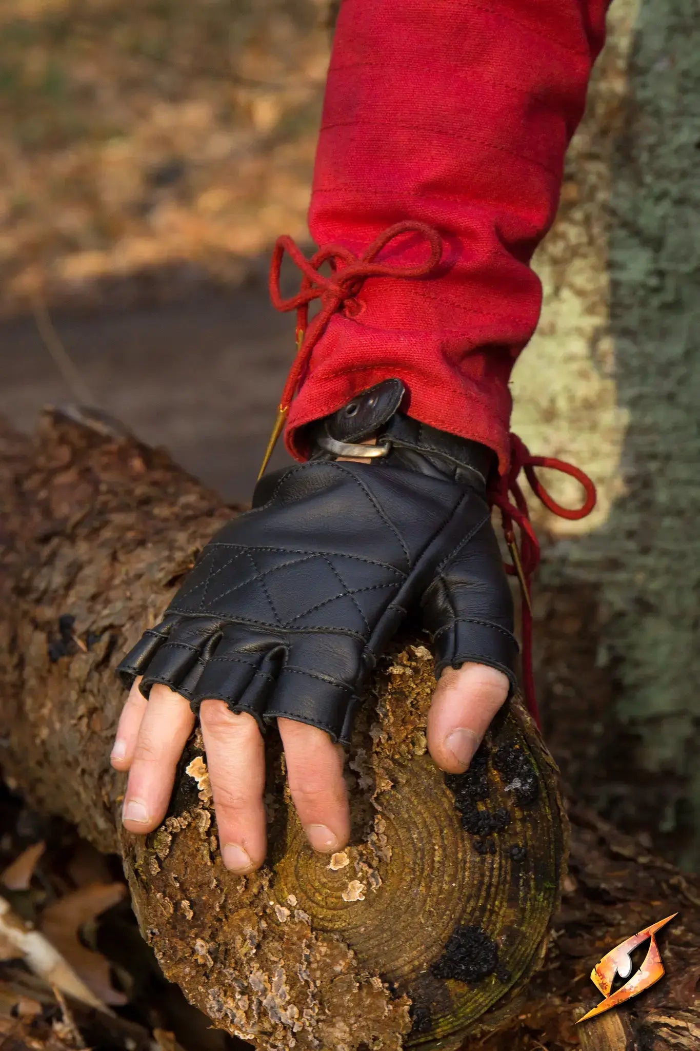 Celtic Gloves Leather in Epic Black color shown on a hand resting on a log, perfect for outdoor activities.