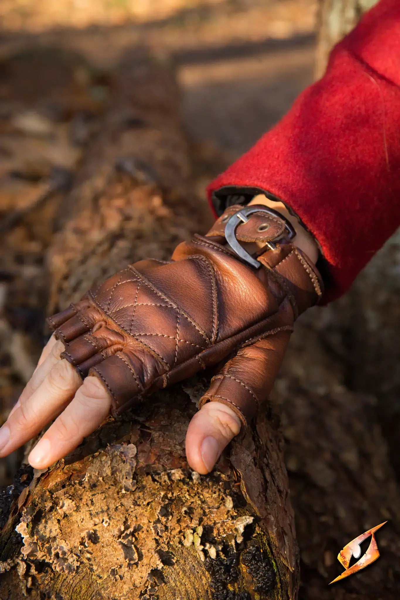Celtic Gloves Leather in ox brown, fingerless design worn on a hand gripping a log outdoors.