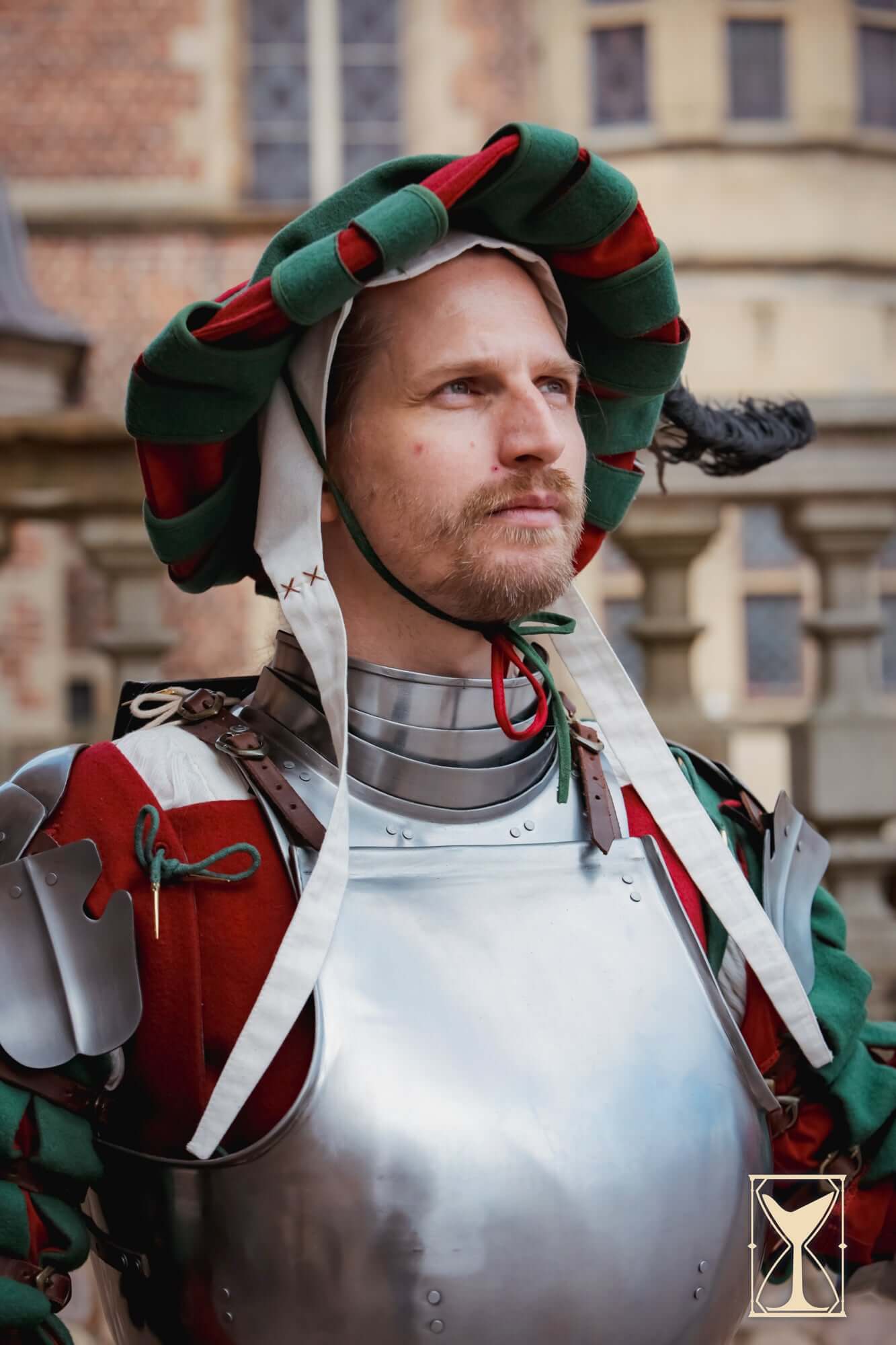 Landsknecht Hat worn by a man in armor, showcasing its bold colors and historical design.