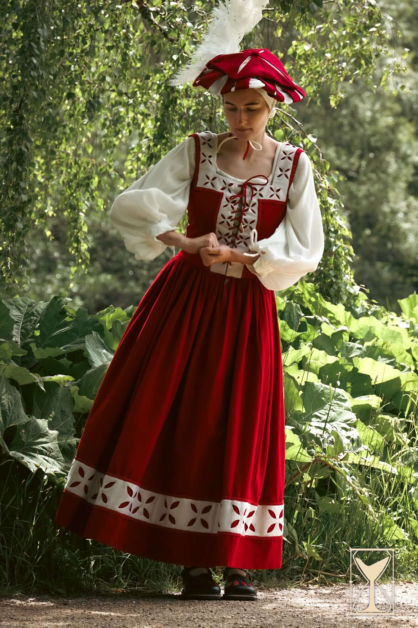 Woman wearing a Kampfrau dress in rich red and white, showcasing historical Landsknecht style in a natural setting.