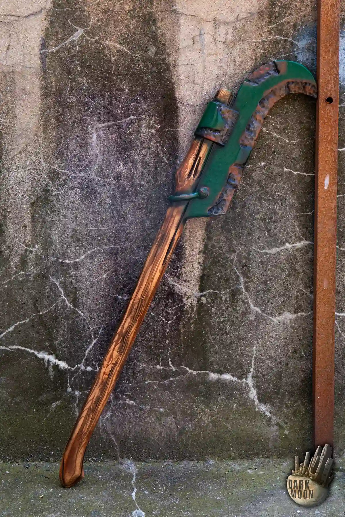 Bush Hook Dark Moon's Red Bush Hook foam gardening tool leaning against a wall.