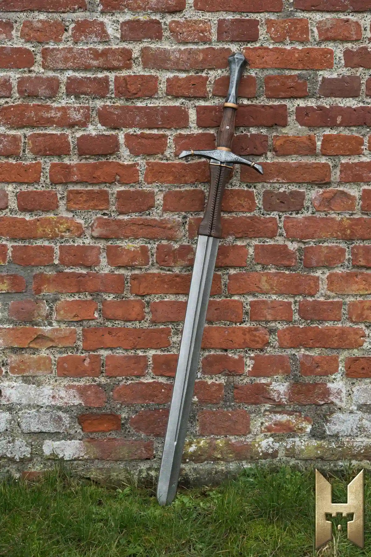 Bastard Sword resting against a brick wall, showcasing its impressive design and craftsmanship.