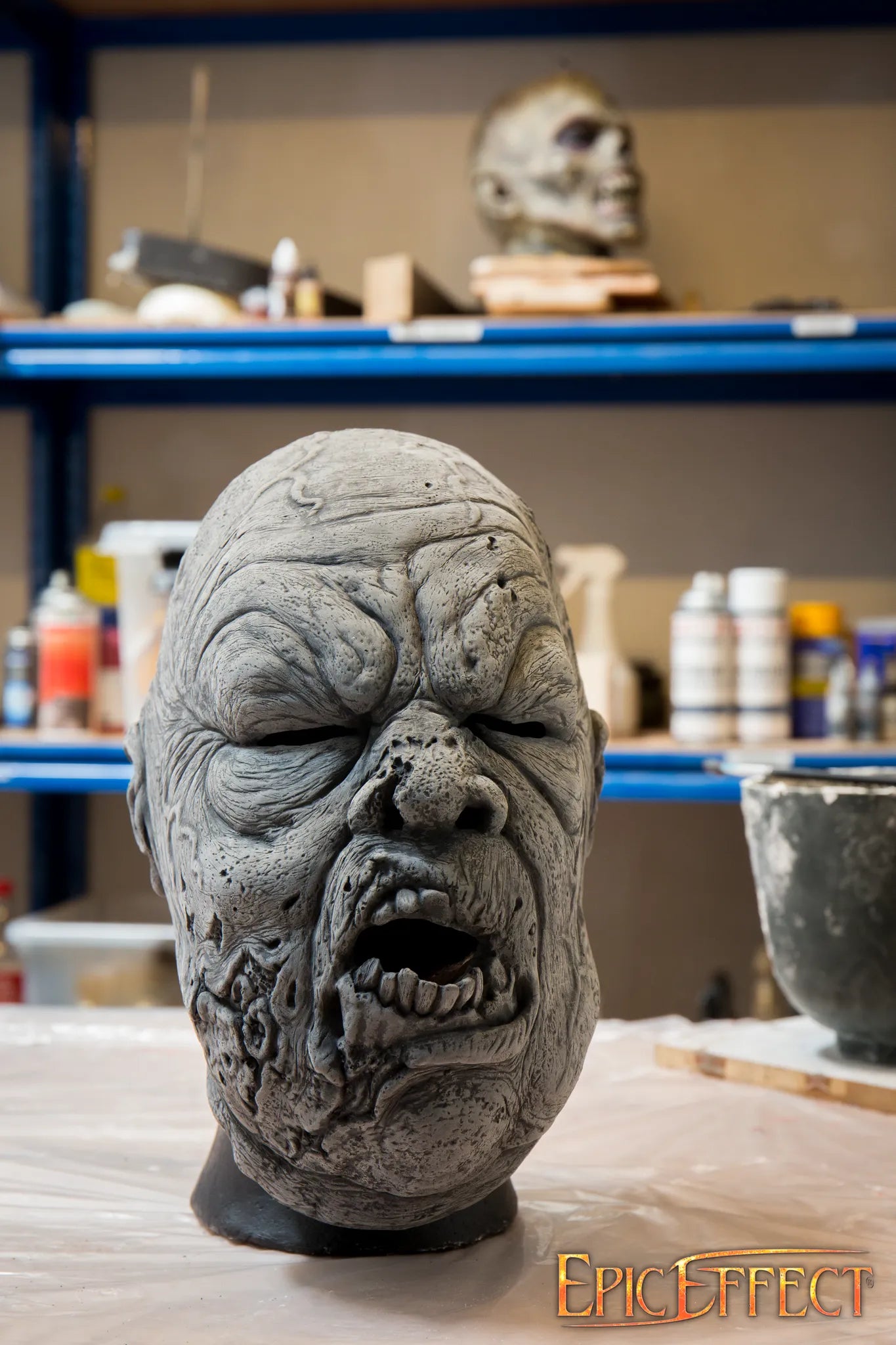Big Rotten Zombie mask sculpture with textured skin and broken features in a workshop setting.