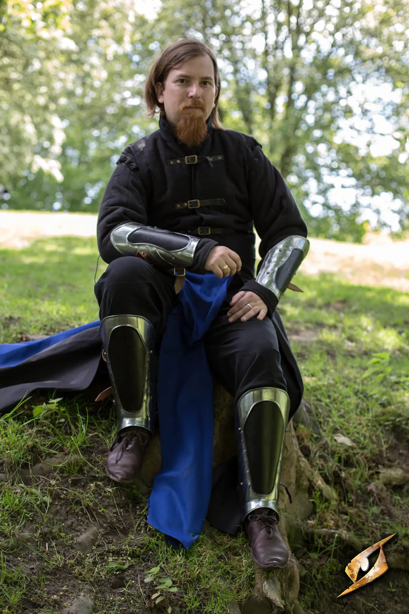Hero showcasing the Black Ice Arm & Leg Protection Set while seated outdoors on a rock.