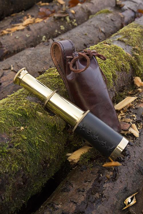 Telescope With Leather Pouch - Brass resting on mossy logs with a leather pouch nearby.