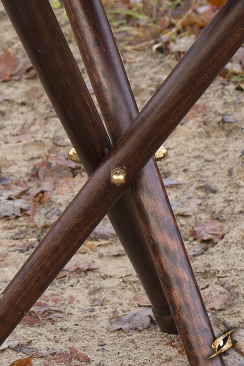 Close-up of sturdy wooden legs of a Tripod Stool assembled on the ground, showcasing its construction and durability.