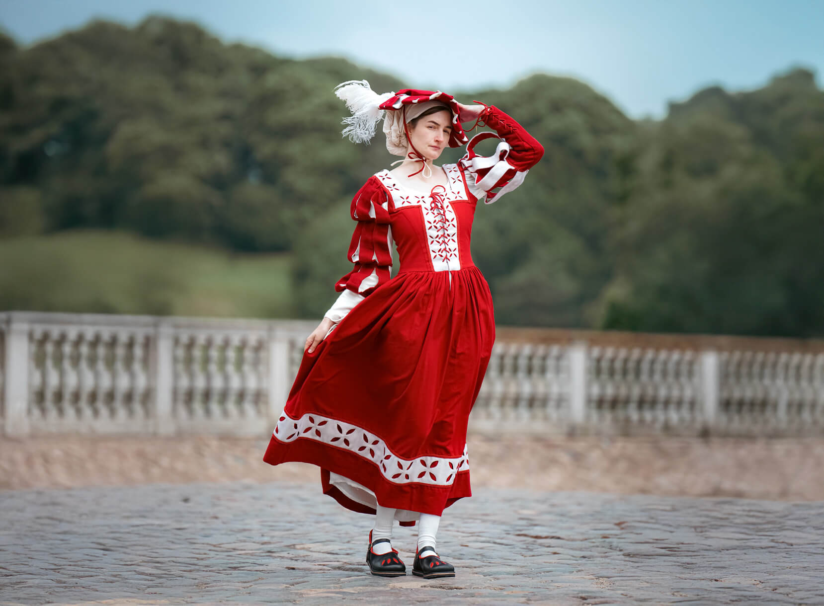 Woman in red Landsknecht dress with feathered hat, Renaissance faire costume.