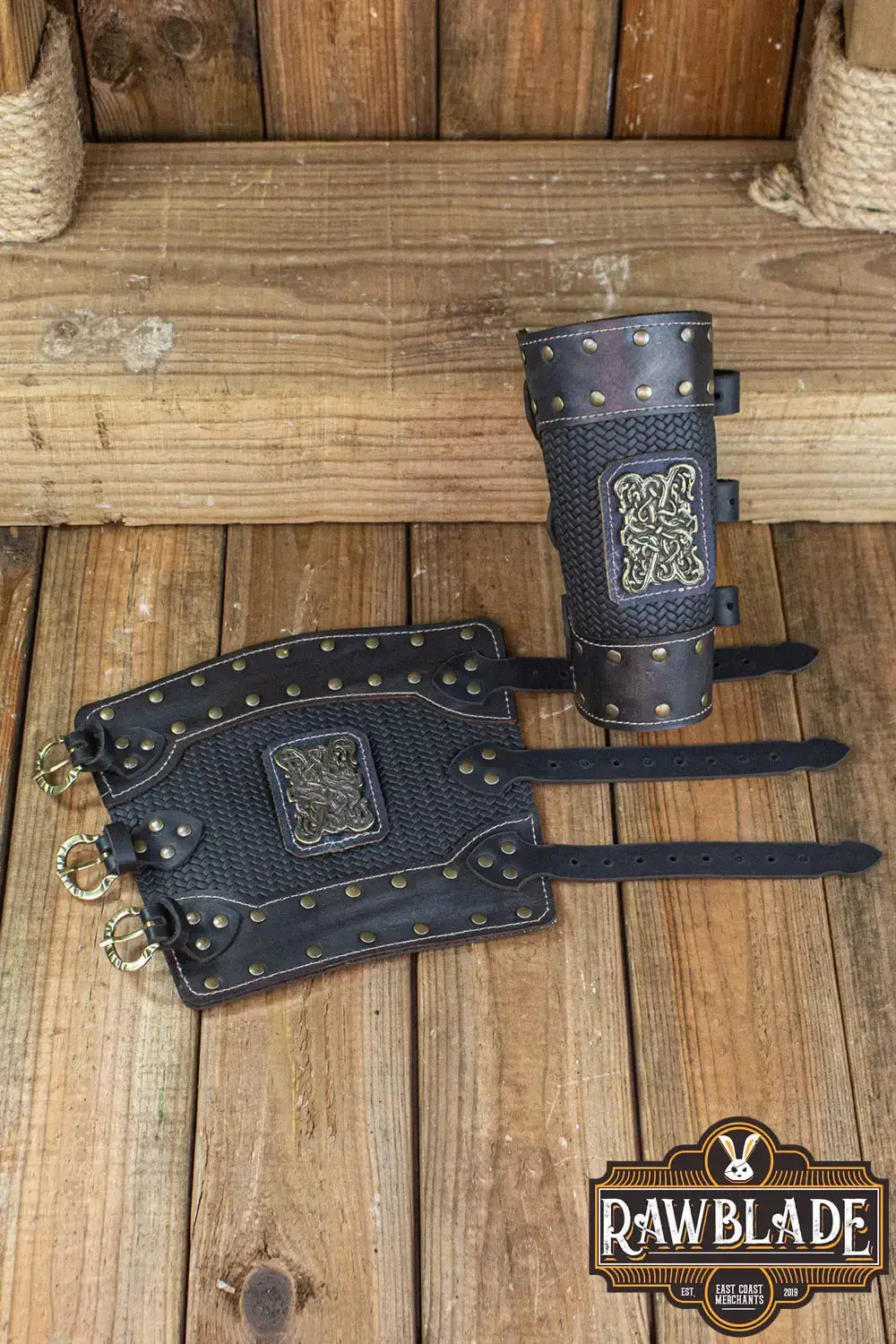 Bruce Bracers displayed on wooden background, featuring layered leather, rivets, and buckles.