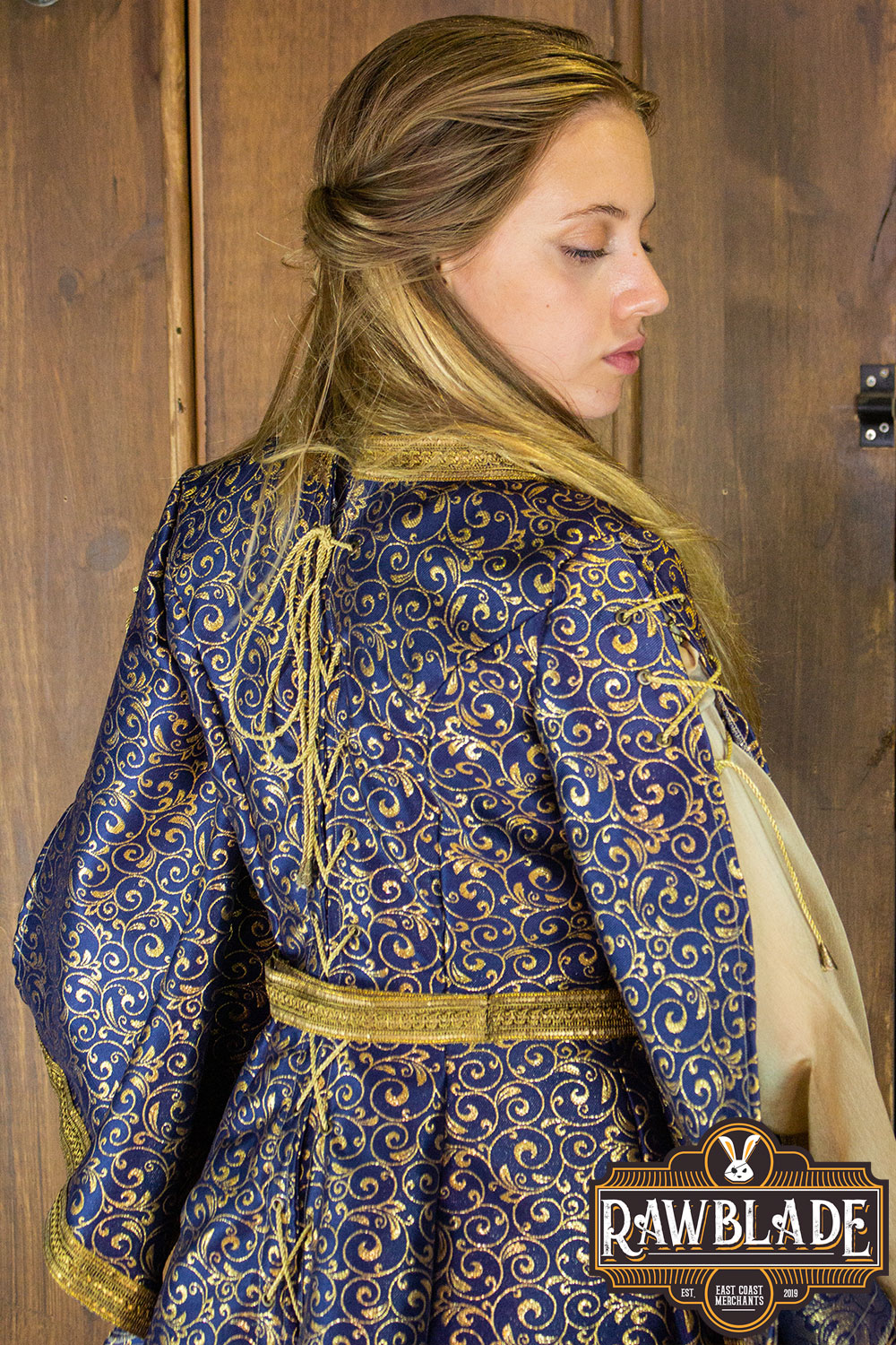 Model showcasing the Aquitania Noble Dress by Rawblade, featuring detailed gold brocade and elegant tulle sleeves.