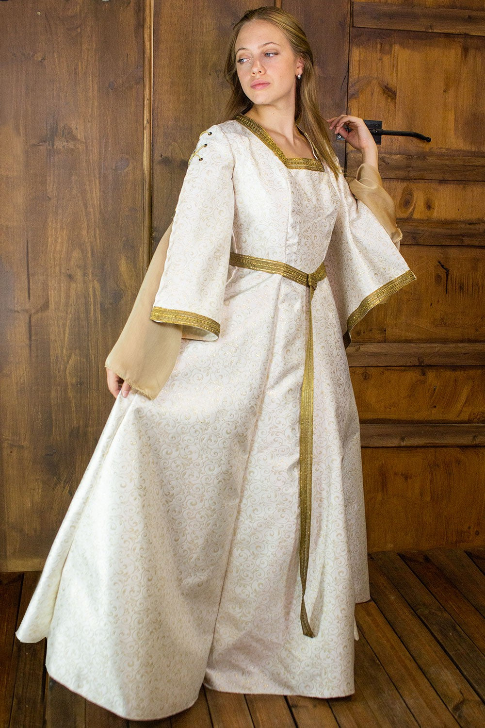Aquitania Noble Dress featuring gold brocade fabric, double tulle sleeves, and intricate trims, perfect for special events.
