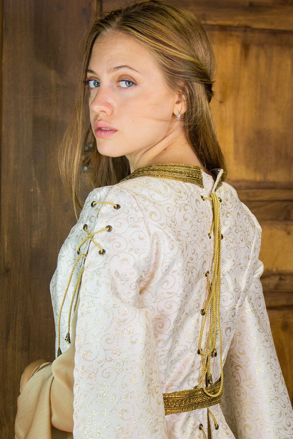 Close-up of a model wearing the Aquitania Noble Dress, featuring intricate gold trims and laces.
