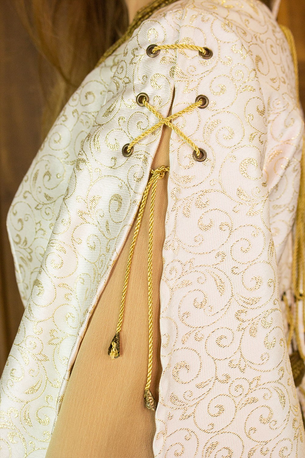 Detail of the Aquitania Noble Dress showcasing the intricate gold lace and tulle sleeves.