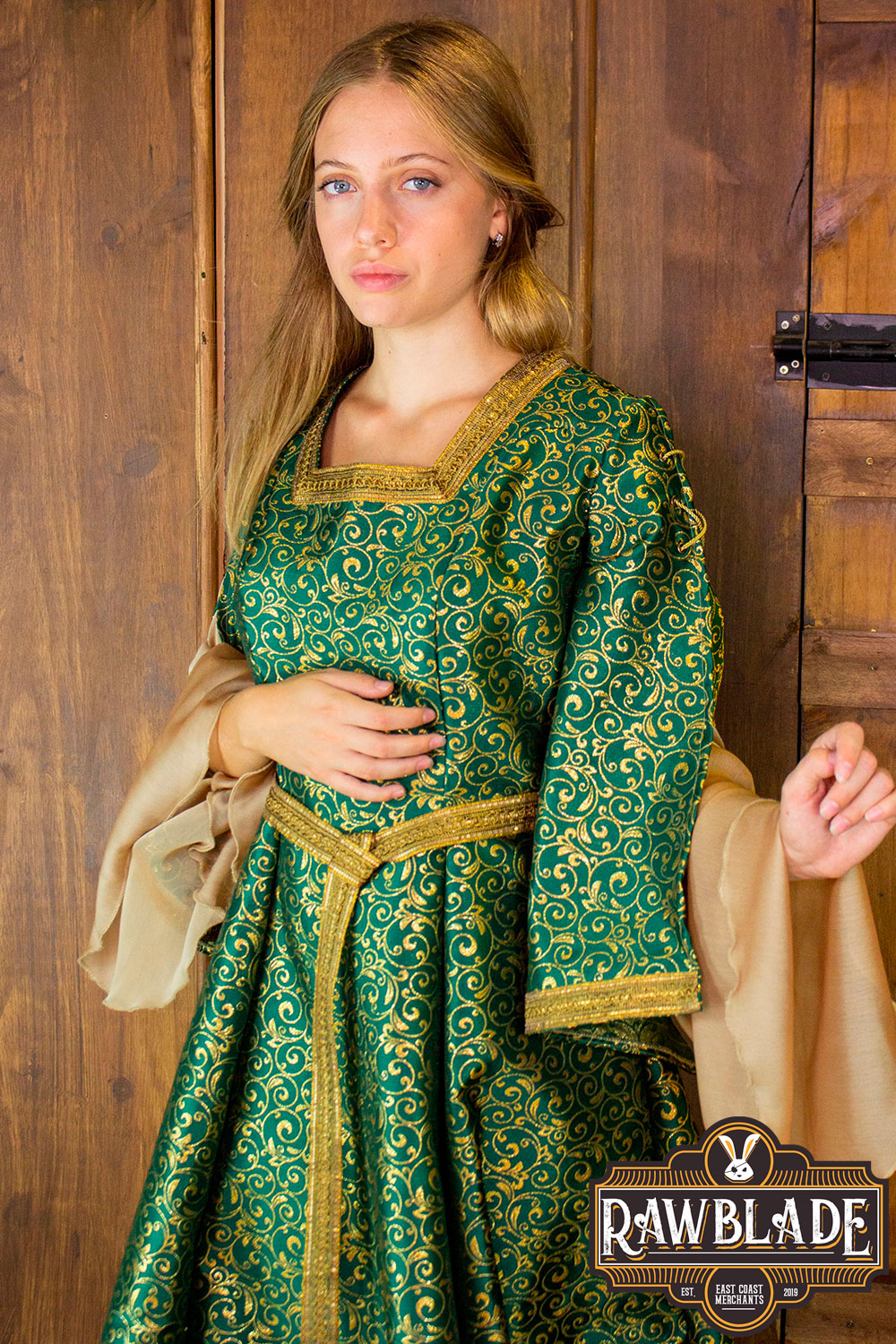 Aquitania Noble Dress featuring a model in intricate gold and green brocade with tulle sleeves and gold trims.