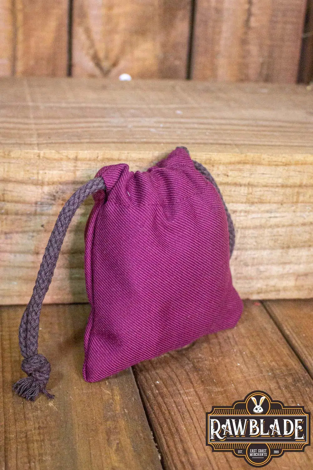 Timber Pouch Premium in purple cotton fabric with a drawstring on a wooden surface.