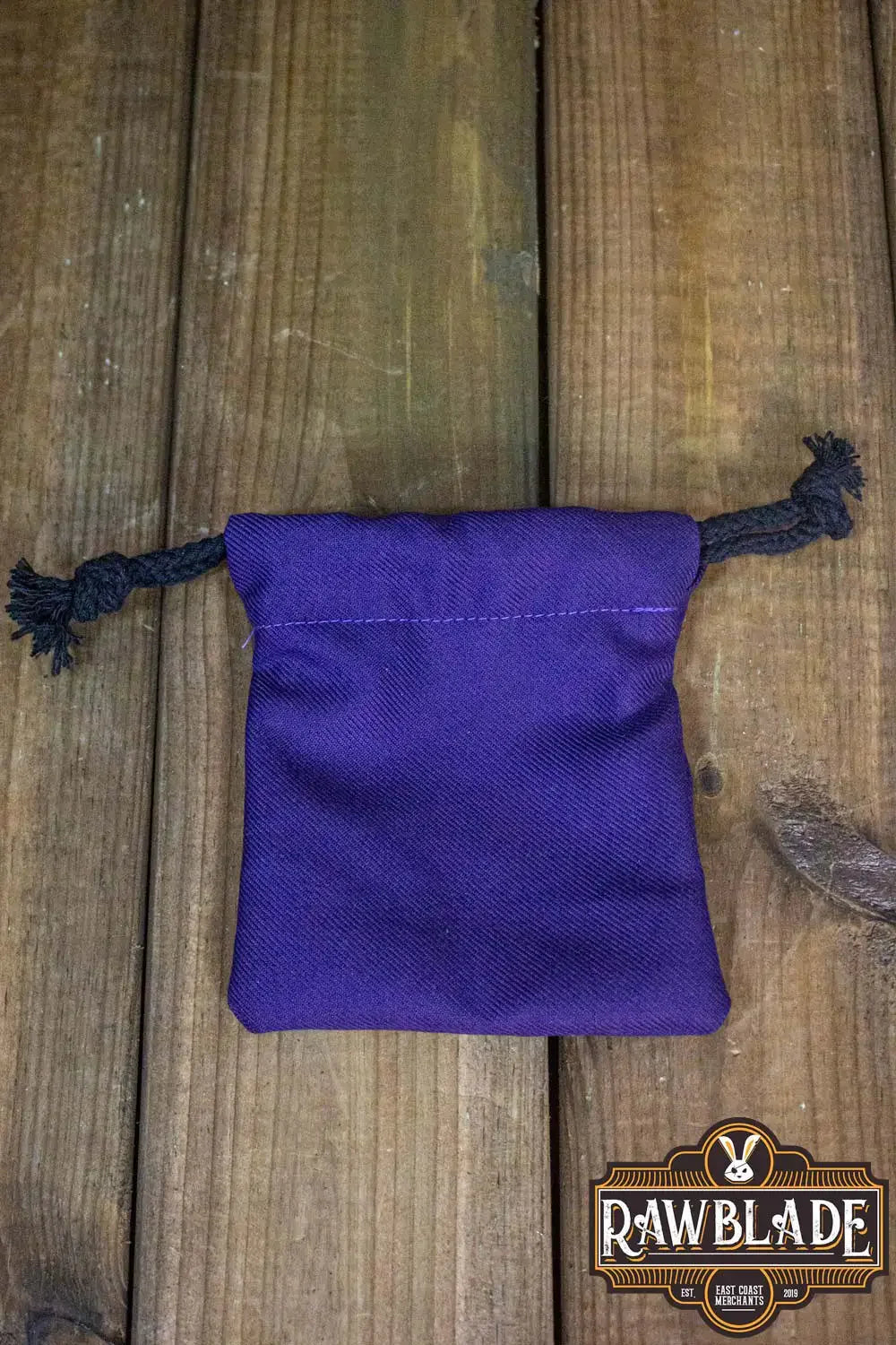 Timber Pouch Premium in purple cotton fabric with panama-style design, featuring drawstring closure, on wooden surface.