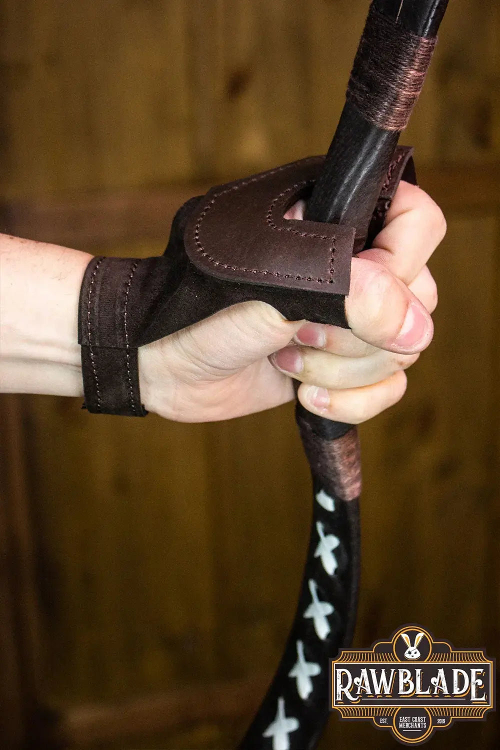 Archery Glove Oren worn on hand gripping a bow, showcasing high quality leather craftsmanship and adjustable wrist.