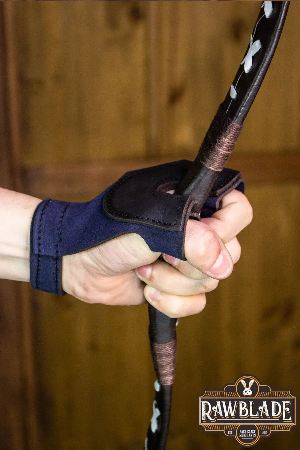 Archery Glove Oren worn while gripping a bow, showcasing high quality leather and adjustable wrist features.