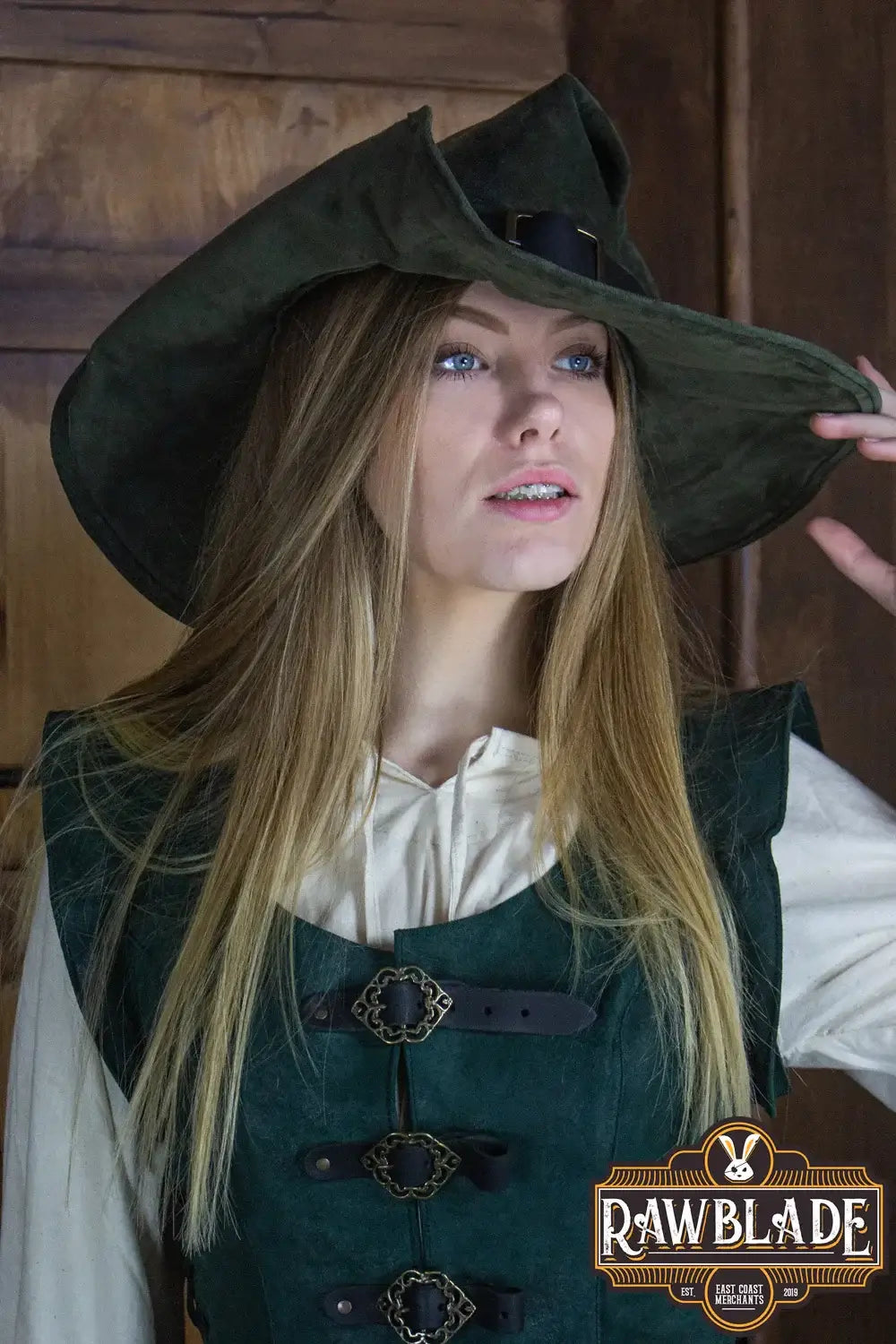 A woman in a pointed green hat, showcasing the Wikka The Witch Hat Split Leather, styled with flexible wings.
