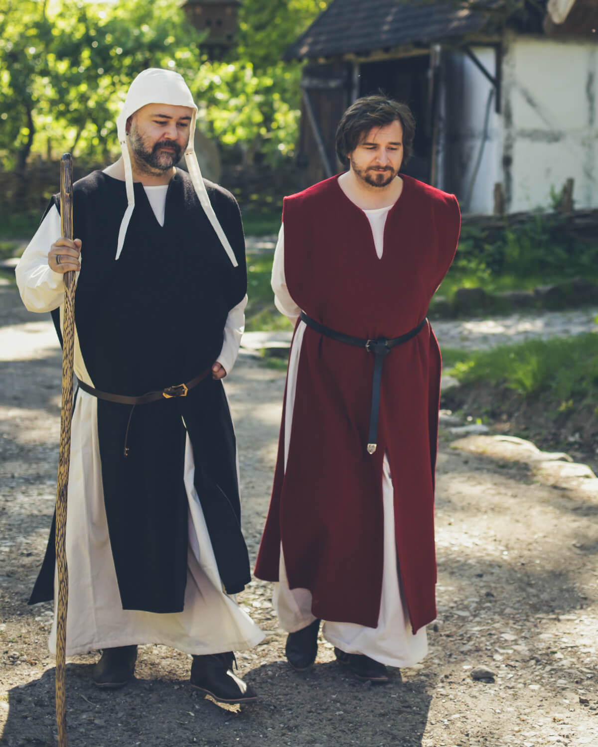 Two men in medieval-inspired tunics and coifs walking outdoors.