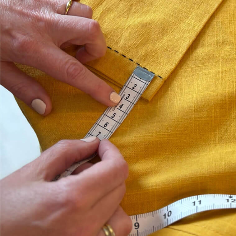 Person measuring yellow fabric with a ruler