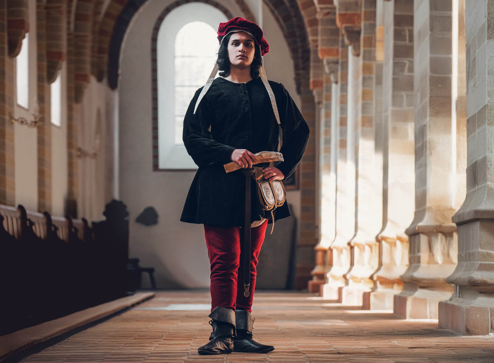 Man dressed in Late Medieval red, black and white costume.