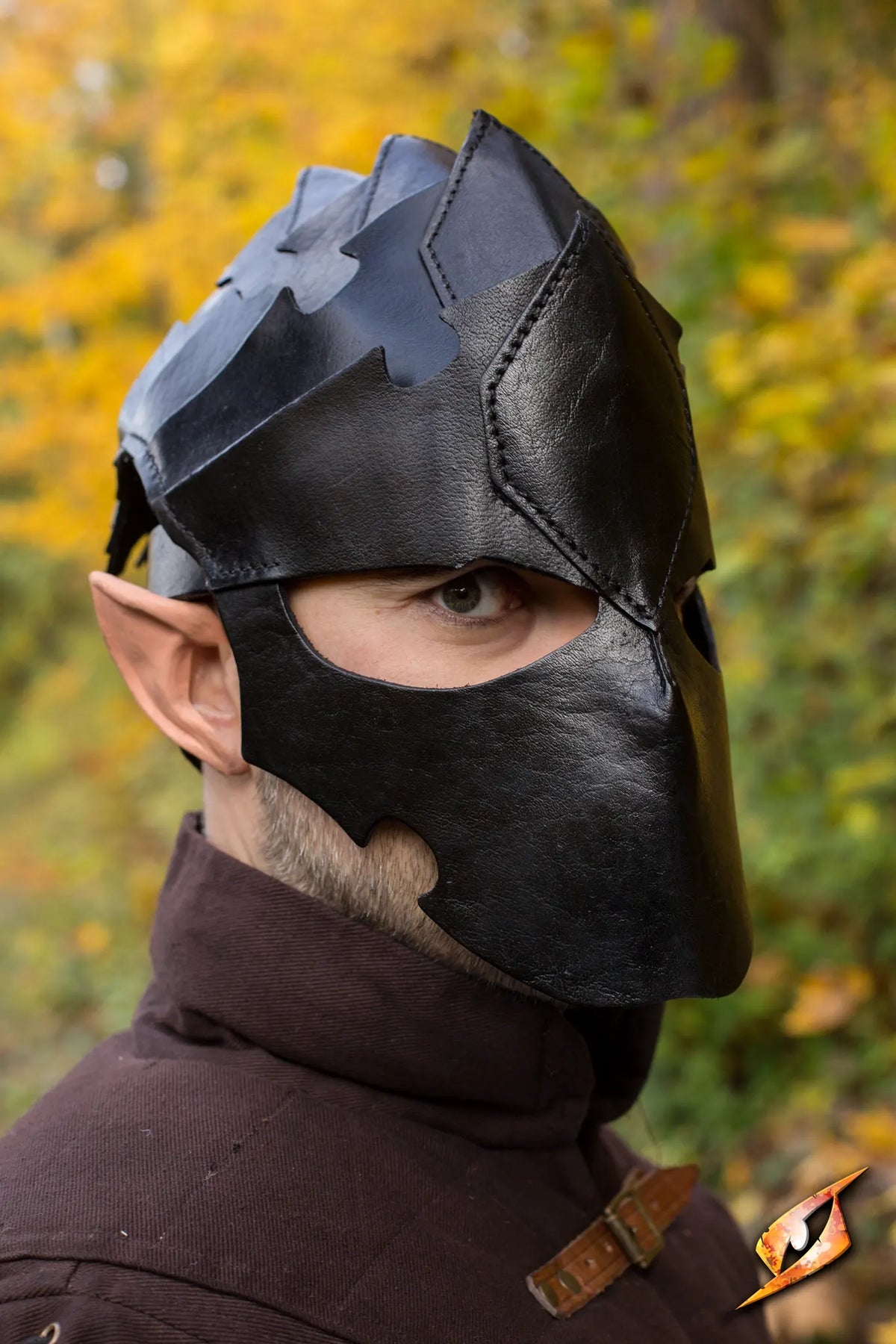 Close-up of a man wearing an Assassin Helmet, showcasing its detailed design against a backdrop of autumn leaves.