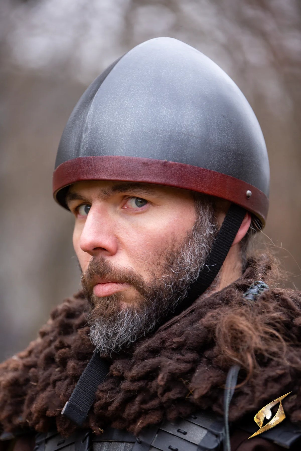 Man wearing RFB Helmet, with a serious expression and fur attire, ready for battle in a medieval setting.