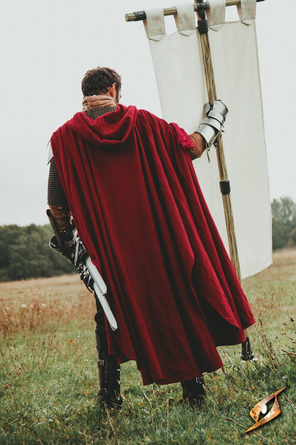 Cape Godfrey Wool worn by a person holding a banner in an outdoor setting.