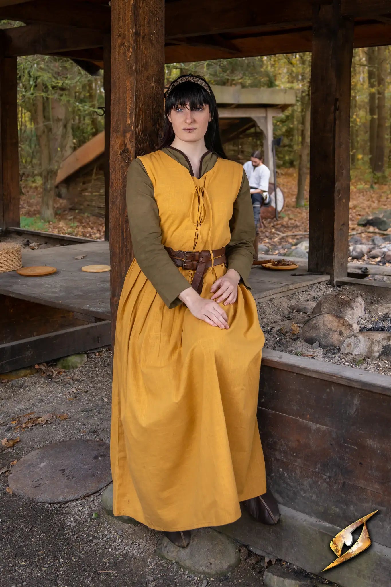 Model wearing the Adelina Dress by Epic Armoury, a yellow medieval dress with a fitted bodice and ribbon ties.