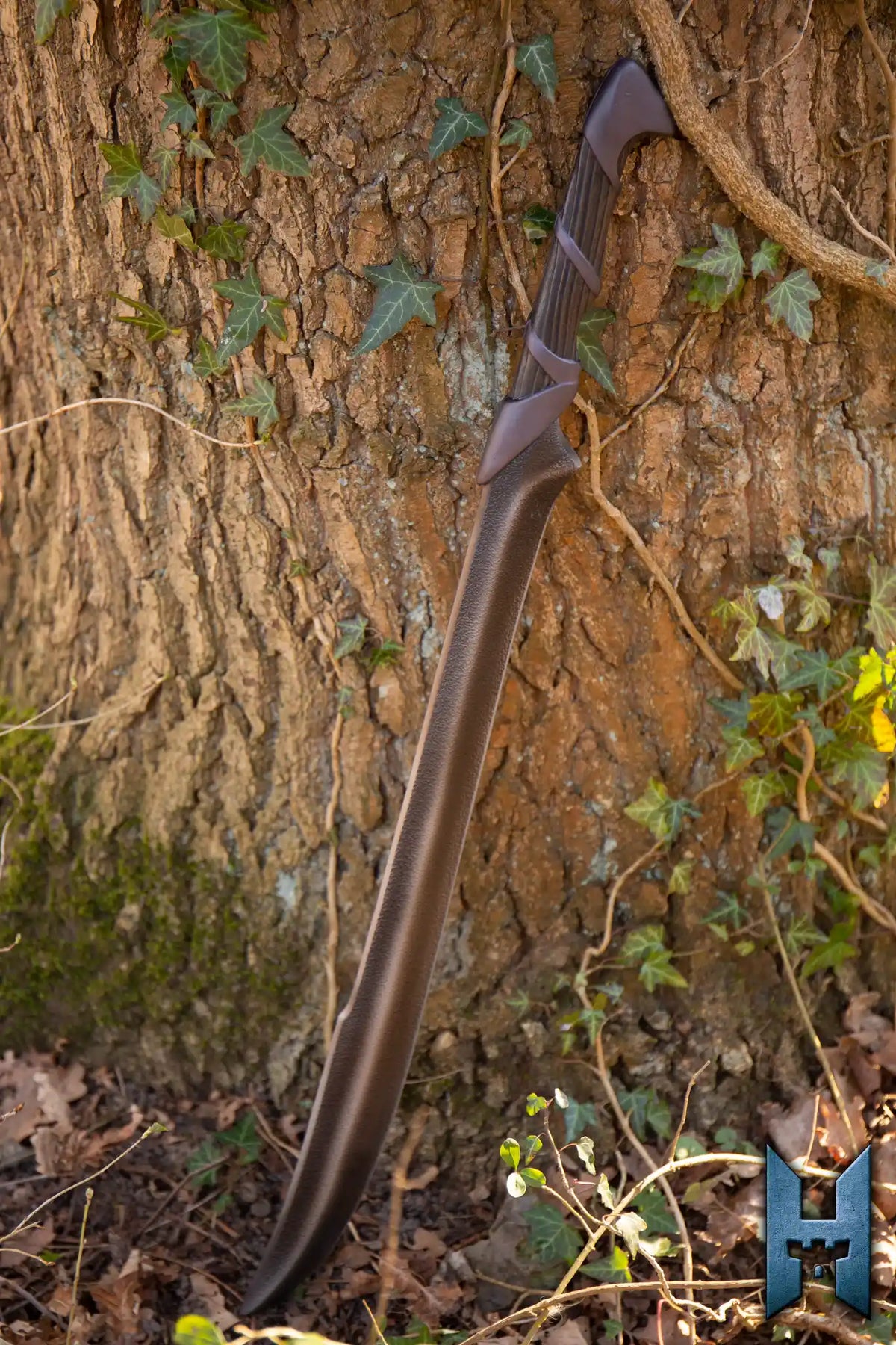 Elven Hunter Blade leaning against a tree in a forest, showcasing its sleek design and craftsmanship.